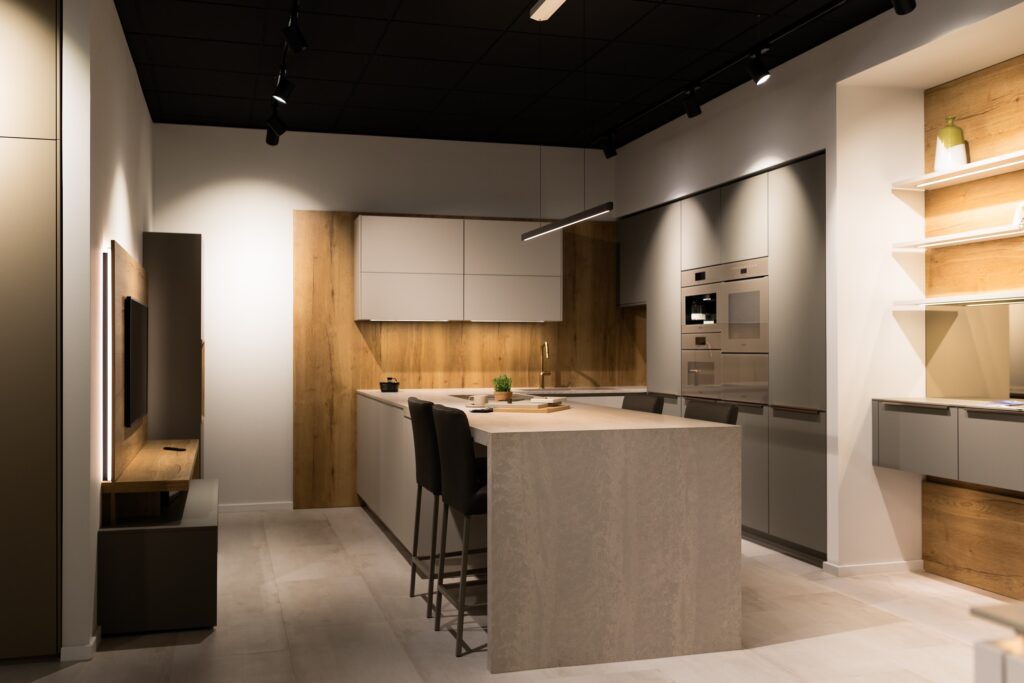 Moderne Küchenausstellung mit Fokus auf indirekte Beleuchtung und Materialmix aus Holz und Betonoptik.