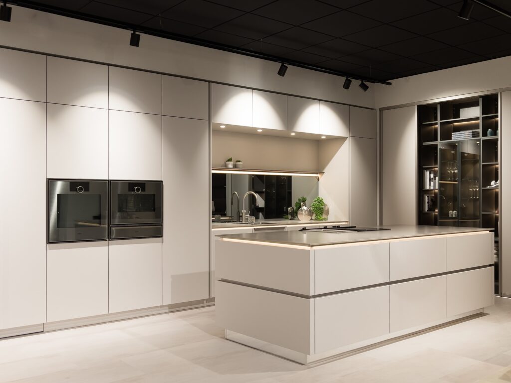 Moderne grifflose Einbauküche in Weiß mit Kochinsel im Küchenstudio Rheinbach.