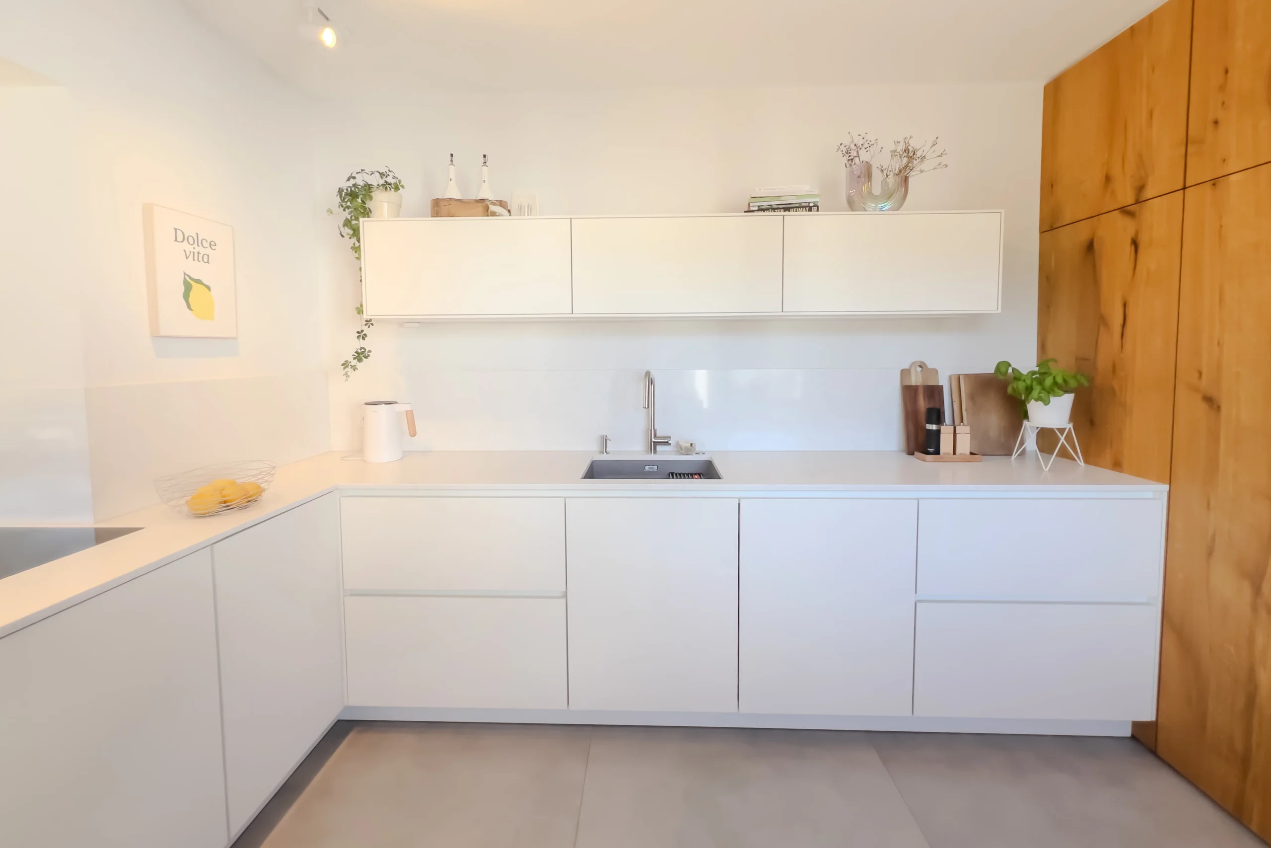 L-förmige weiße Küche in Alfter mit Hängeschränken, weißer Glasrückwand und Massivholzhochschrank