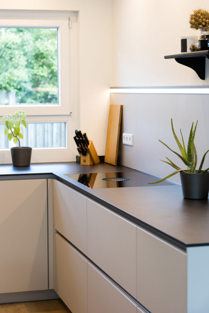 Arbeitsbereich mit flächenbündigem BORA Kochfeldabzug, schwarzer Arbeitsplatte und LED-Nischenbeleuchtung.