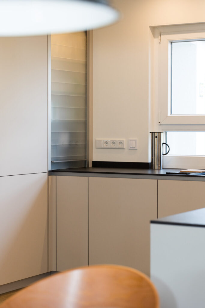 Funktionale Küchenecke mit aufgesetztem Rollladenschrank für Küchengeräte neben dem Fenster.
