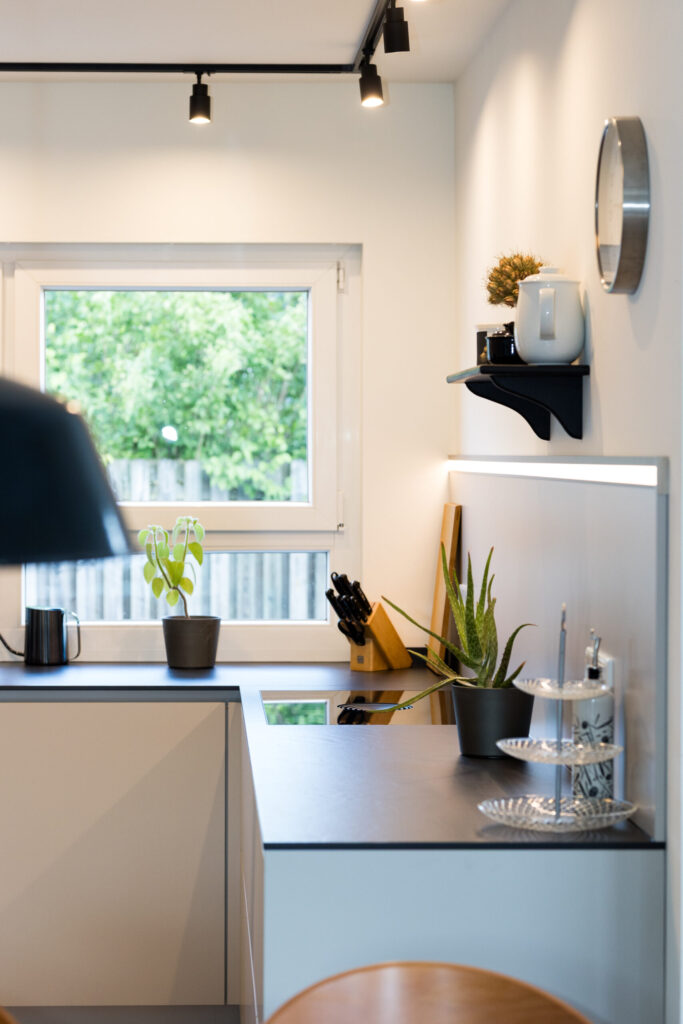 Seitenansicht der Arbeitsfläche mit dekorativem Wandboard, indirektem Lichtband und Nischenpaneel.