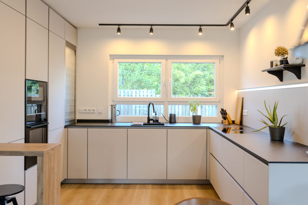 U-Küche mit Arbeitsbereich direkt am Fenster, schwarzer Franke Spüle und deckenhohen Schränken.