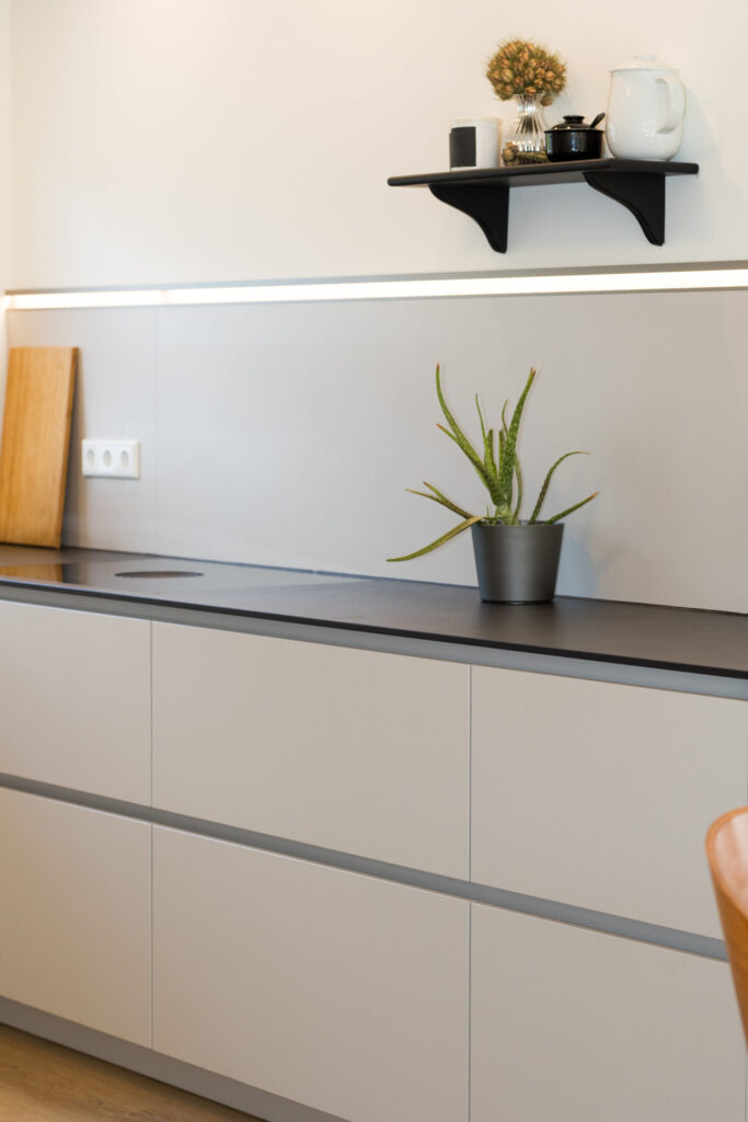 Grifflose Nobilia Unterschränke mit schwarzer Arbeitsplatte, Aloe Vera Pflanze und Naber LED-Nischenlicht.