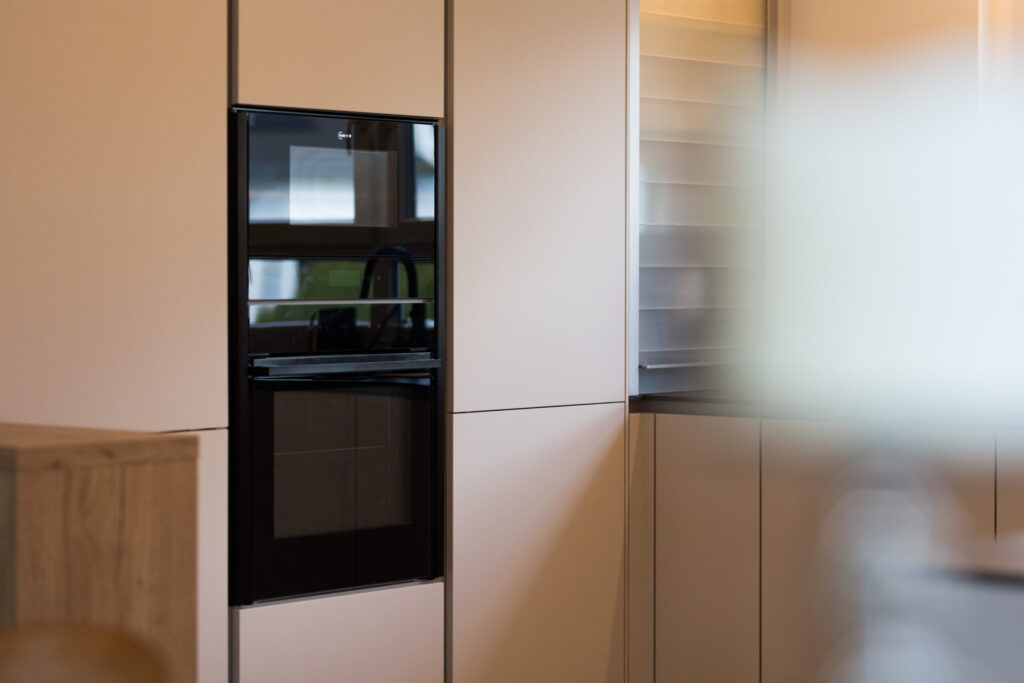 Schwarze NEFF Einbaugeräte bündig integriert in matte grifflose Küchenschränke.
