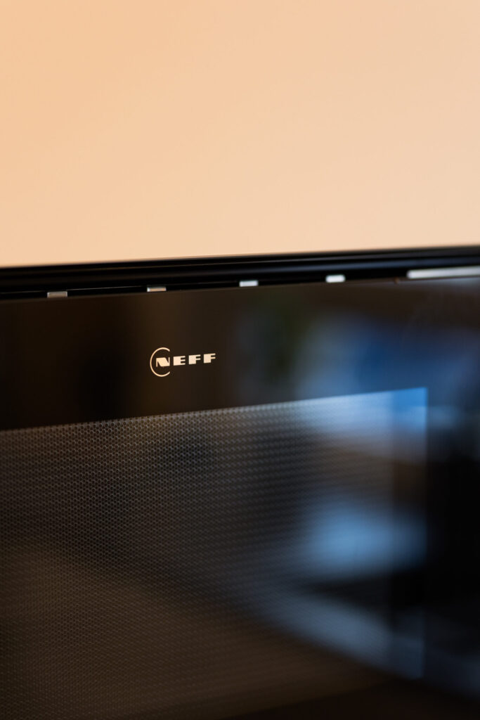 Nahaufnahme des NEFF Logos auf der Glasfront des integrierten Küchen-Einbaugeräts.