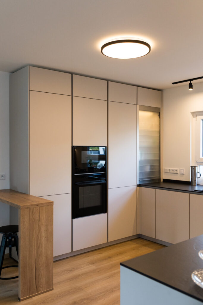 Deckenhohe Schrankwand mit integriertem NEFF Backofen, Rollladenschrank und Thekenelement.