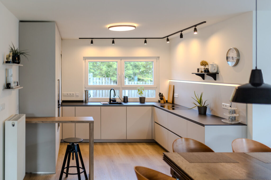 Offene Designküche mit angegliedertem Bartresen in Holzoptik und Blick auf den Esstisch.