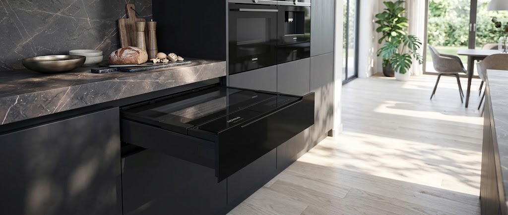 Dunkle Küche mit Marmor-Arbeitsplatte und schwarzen Siemens Einbaugeräten: Backofen, Kaffeevollautomat und geöffnete Einbauschublade